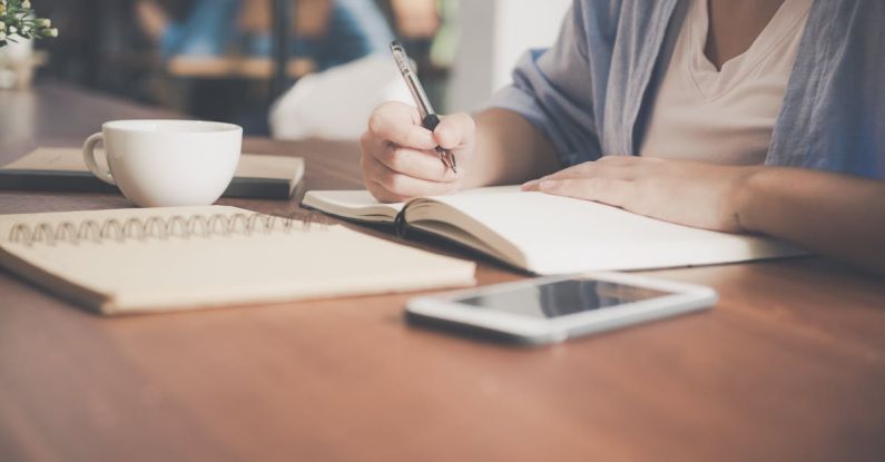 Online Course - Woman Writing on a Notebook Beside Teacup and Tablet Computer