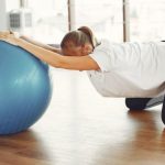 Healthcare Future - Side view of female sportswoman while group training with fitness ball during prenatal workout with crop friend in modern gym during daytime