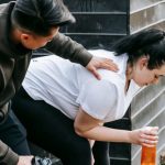 Trust Transparency - Sportsman clapping shoulder of plump tired female trainee sitting near net fence with bottle of water after training in autumn park