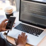 Remote Working - Person Holding Smartphone while using Laptop