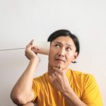 Difficult Question - Pensive ethnic man listening to answer in paper cup phone