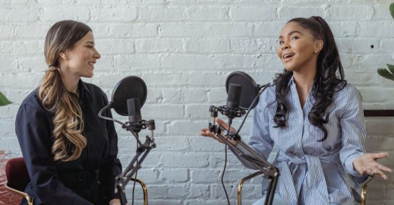 Remote Interview - Smiling African American female guest gesticulating while having interview with journalist sitting near mic