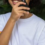 Effective Study - Cheerful African American girl in stylish T shirt looking at camera and enjoying exploration with magnifier