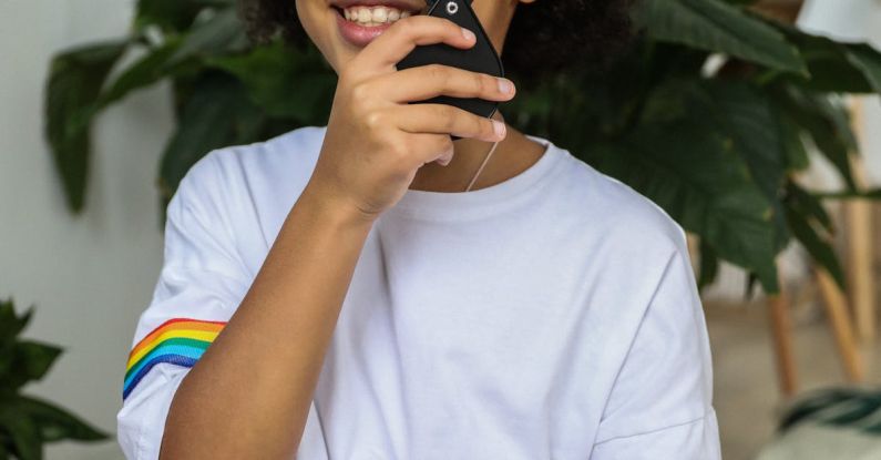 Effective Study - Cheerful African American girl in stylish T shirt looking at camera and enjoying exploration with magnifier