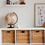 OER Globe - Comfortable bed with toys globe and paintings placed on wooden cabinet with wicker boxes and soft white rug with toy house on floor